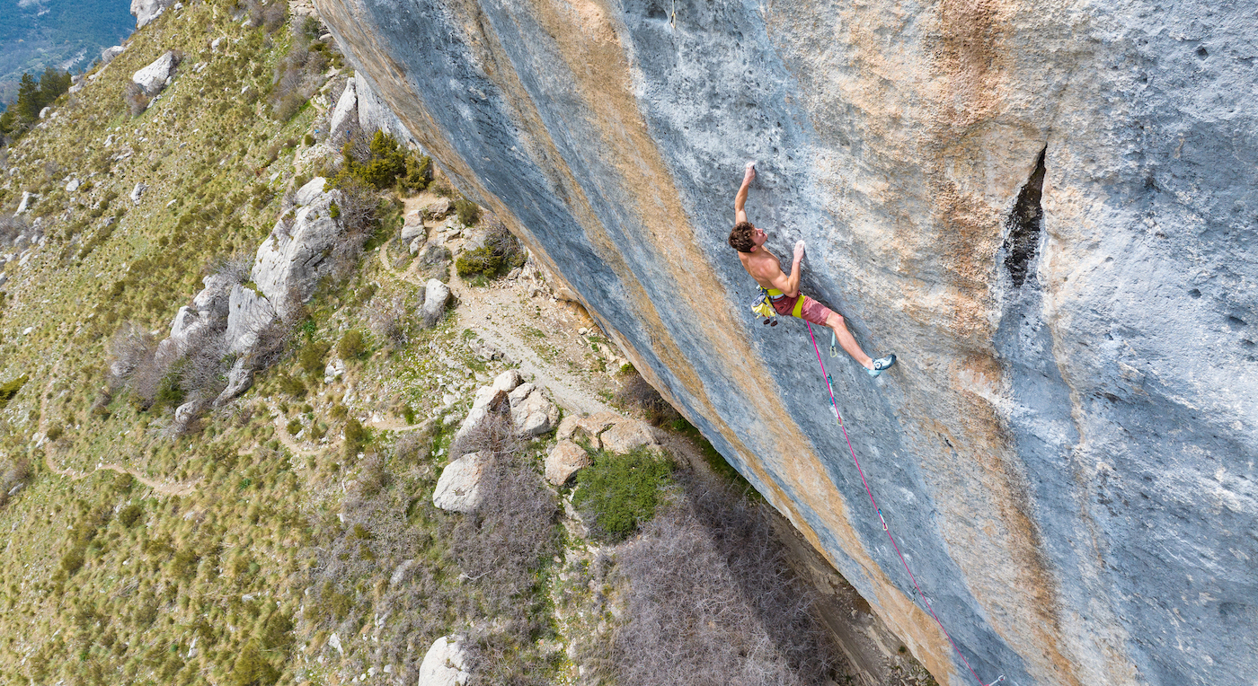 Young, male rock climber high up on a cliff band in France.